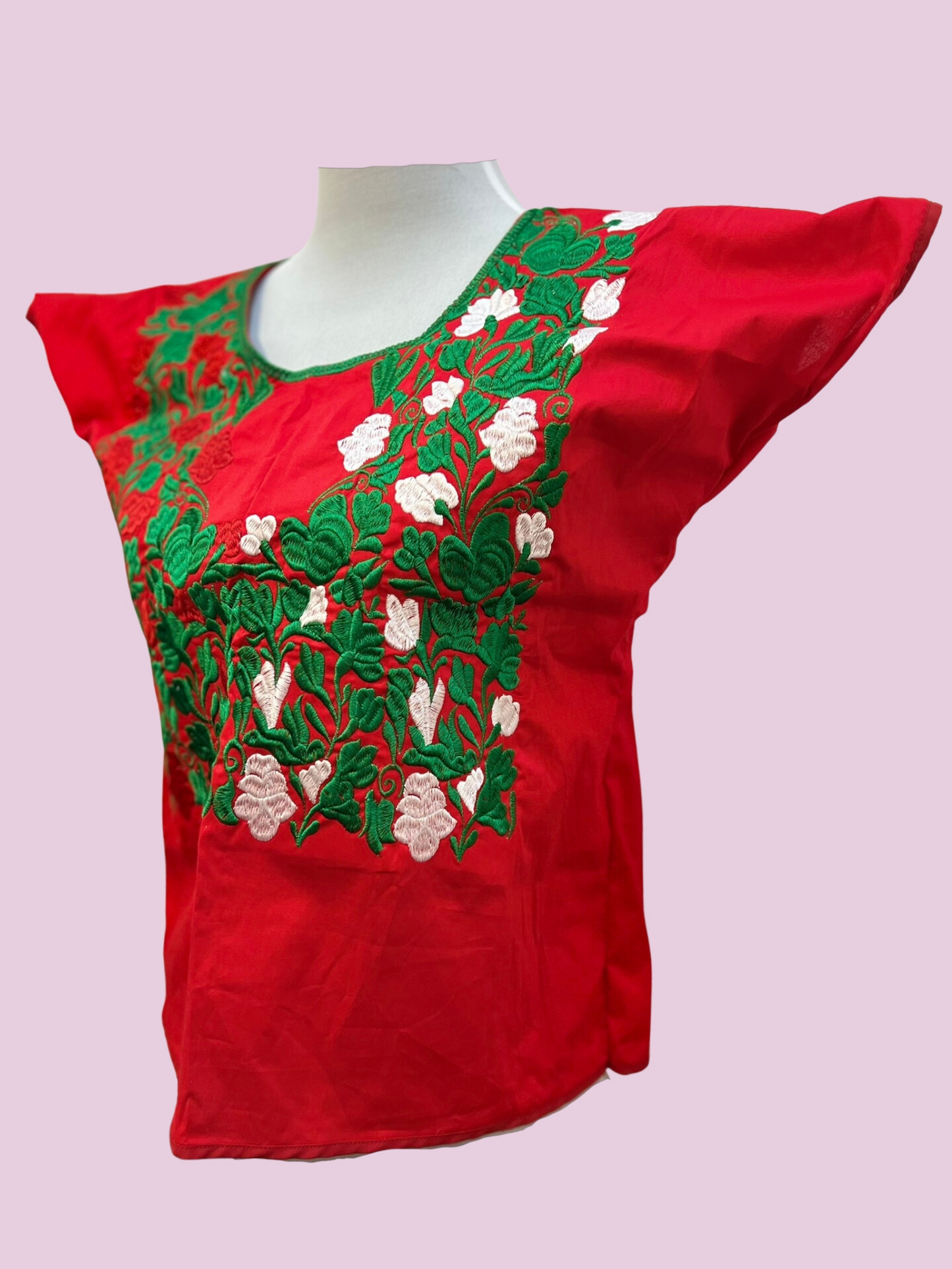 Blusa en fondo rojo, con flores en tonos verde y blanco