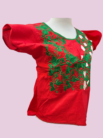 Blusa en fondo rojo, con flores en tonos verde y blanco