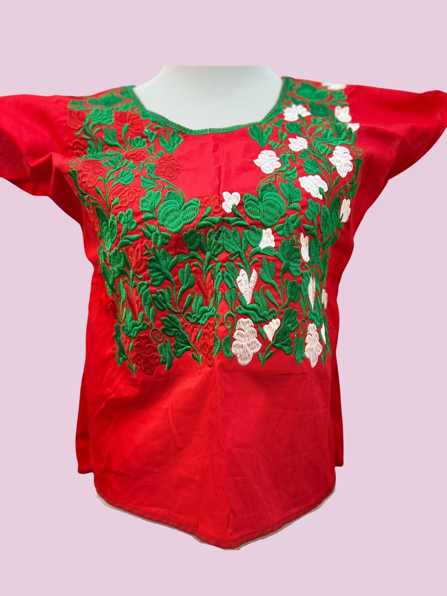 Blusa en fondo rojo, con flores en tonos verde y blanco